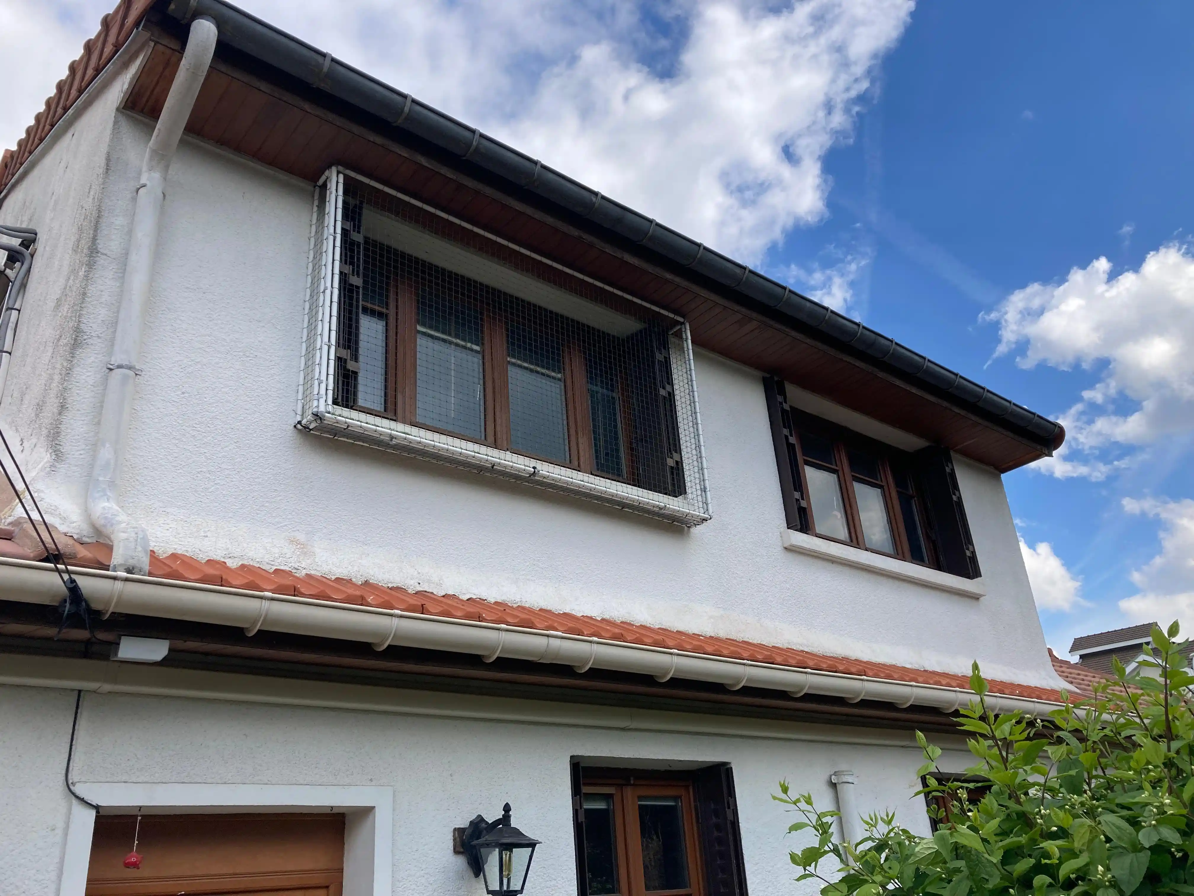 Enclos extérieur fixé à une fenêtre avec filet de protection pour chat