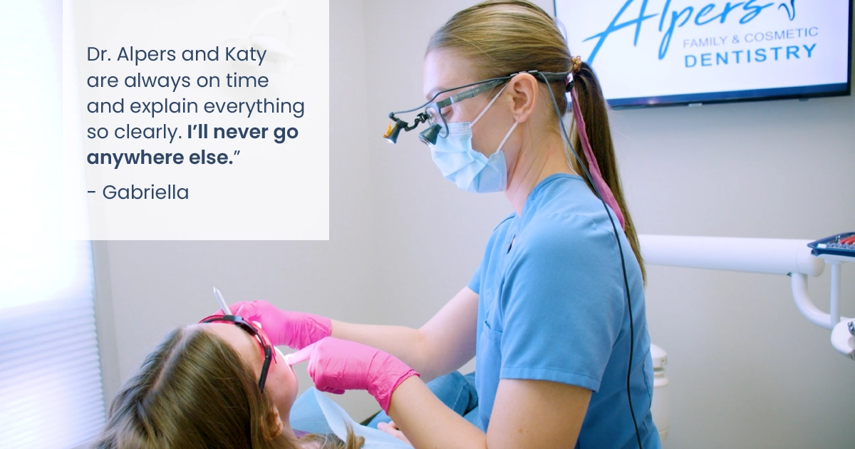 Dental hygienist performing a cleaning on a patient in our Scottsdale office. Patient quote says, "Dr. Alpers and Katy are always on time and explain everything so clearly. I'll never go anywhere else." - Gabriella