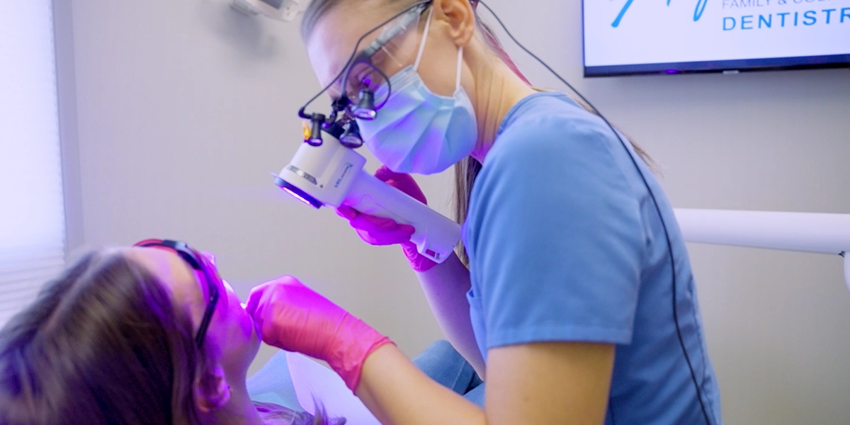 Dental hygienist at Alpers Dentistry performing a screening for oral cancer in a young adult patient