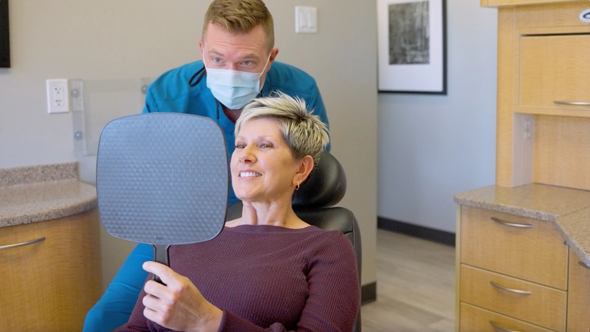 Dr. Kristopher Alpers showing a Scottsdale cosmetic dentistry patient her smile results during a dental appointment.