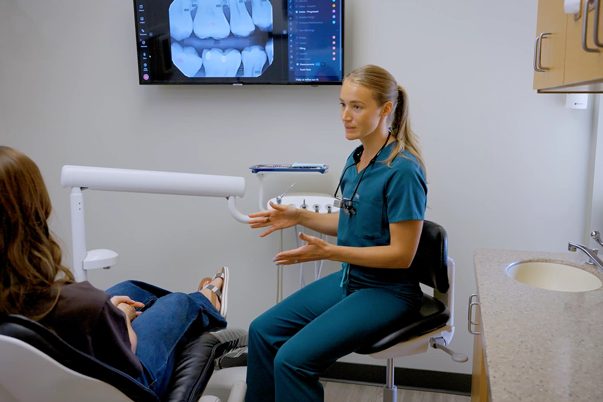 Dental hygienist reviewing dental X-rays with a patient to look for signs of tooth decay and changes that may not be causing symptoms.