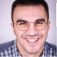 Un jeune homme souriant portant des lunettes