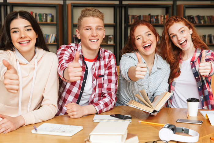 Un groupe d'étudiants qui lèvent le pouce dans une bibliothèque.