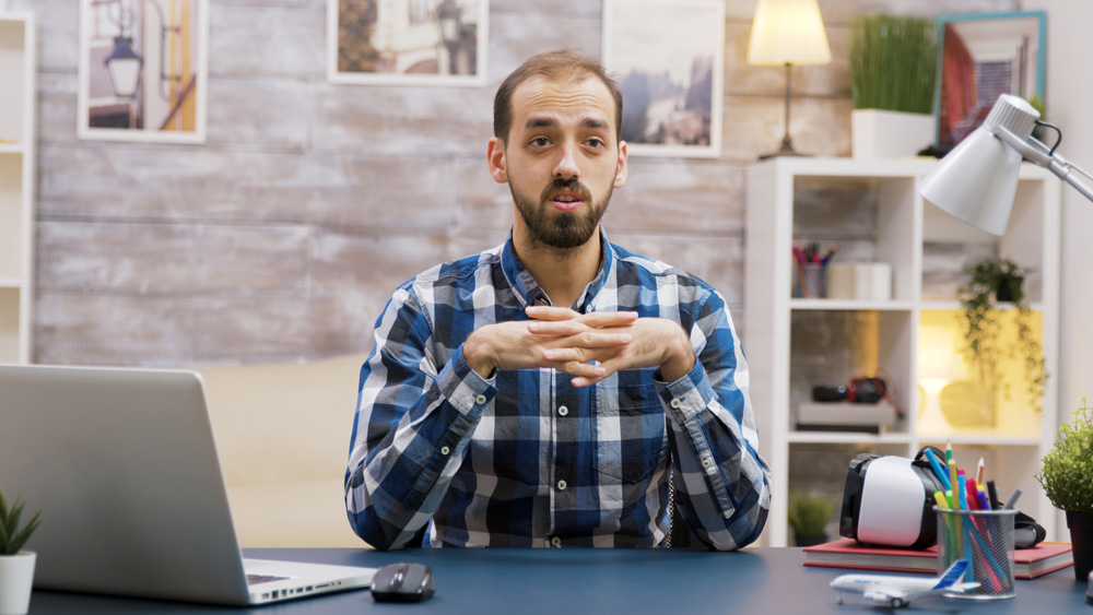 Un homme assis à un bureau avec un ordinateur portable devant lui.