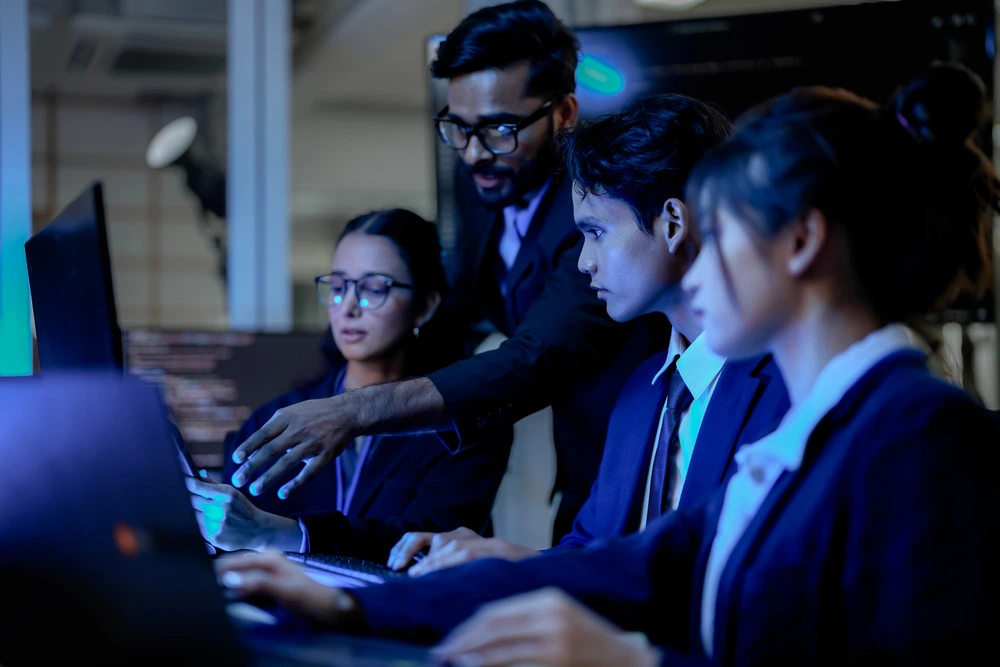 Cybersecurity professionals learning and working together at computer screens