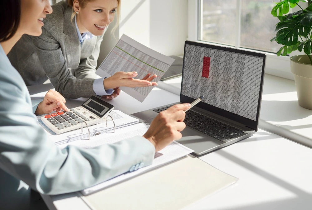 Two ladies checking values in an Excel spreadsheet