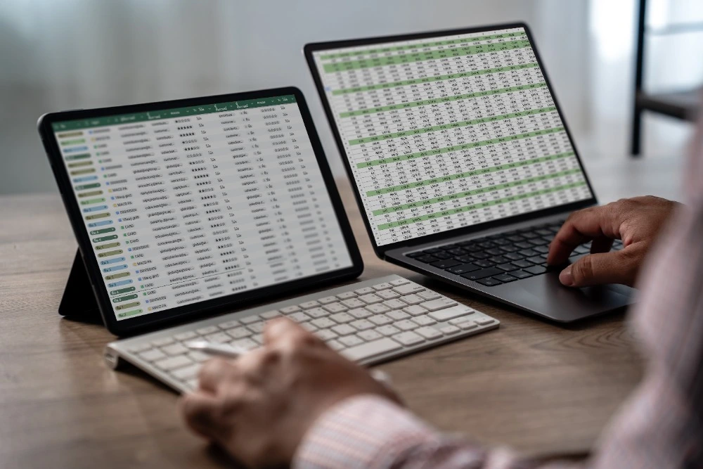 A photo of someone using Excel on a laptop with a second screen