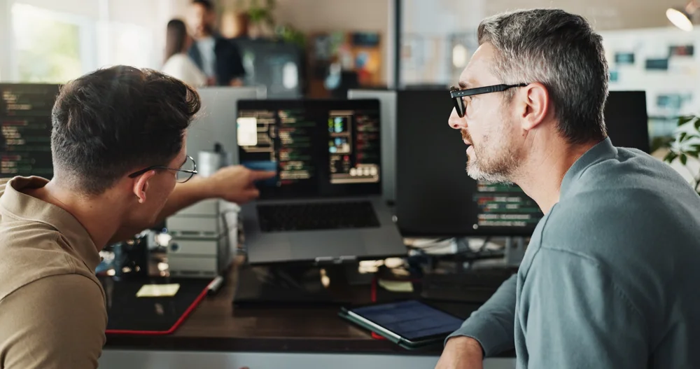 Two professionals reviewing data and software together at a workstation