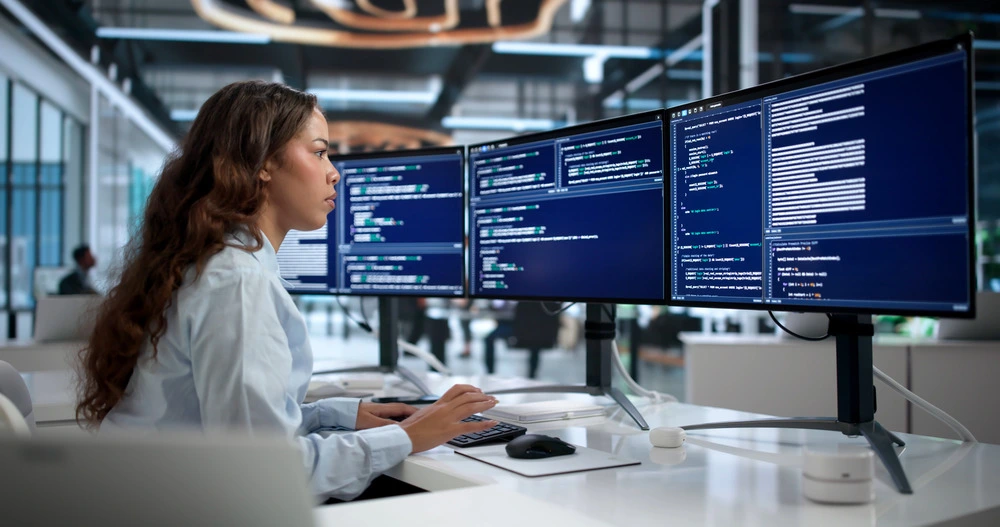 Cloud technology professional working across multiple technical computer screens
