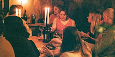 People sat round a table enjoying drinks and chatting in a candle lit room