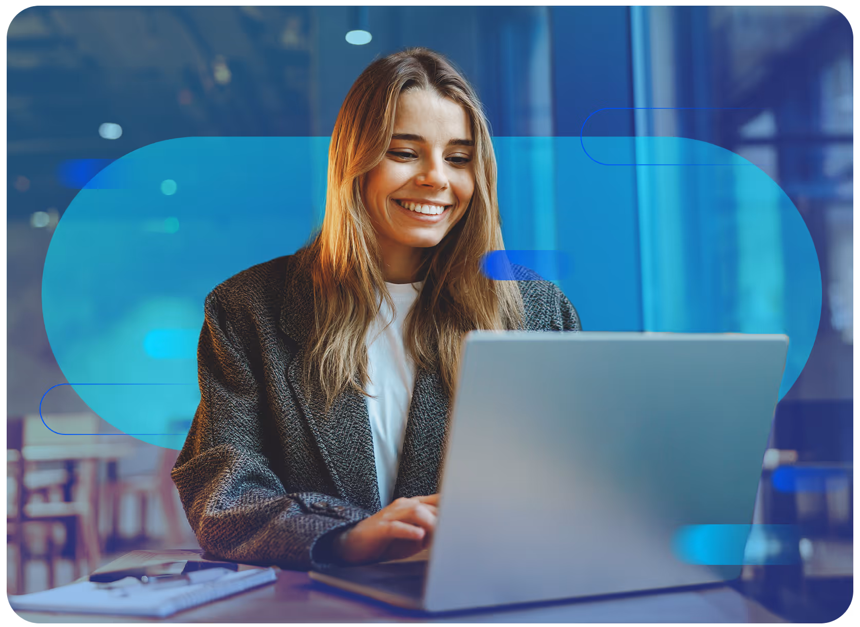 Mulher no escritório, usando o computador e sorrindo.
