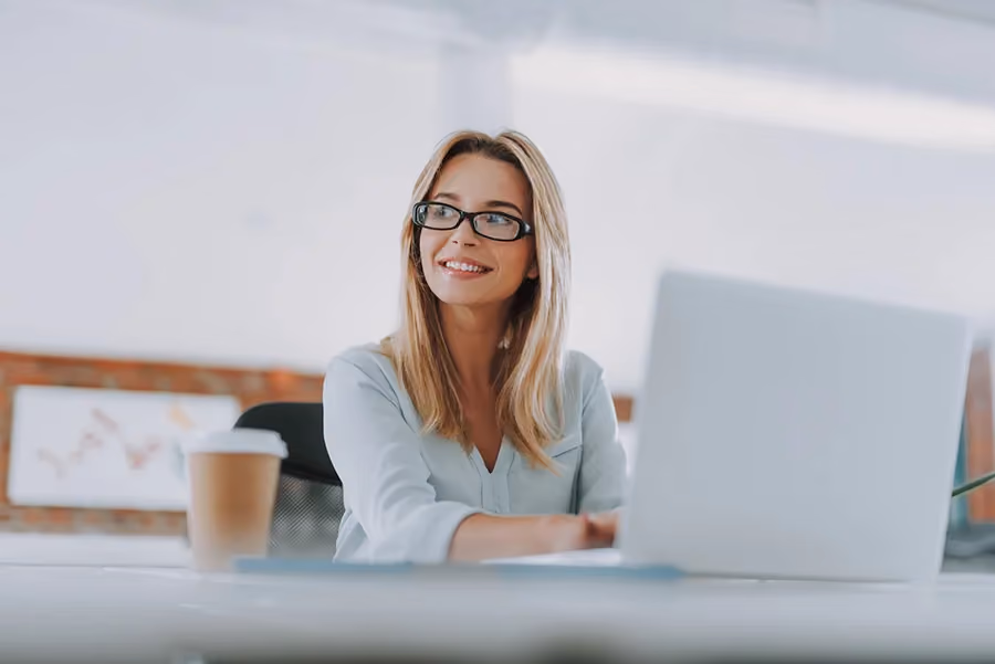 Mulher usando laptop com expressão feliz, representando as oportunidades de parceria com a CIAL e o Número D-U-N-S®.