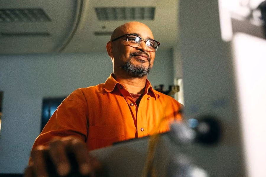 Homem sorrindo enquanto lê um artigo sobre a transição da Indústria 4.0 para a 5.0, explorando novas tendências tecnológicas.