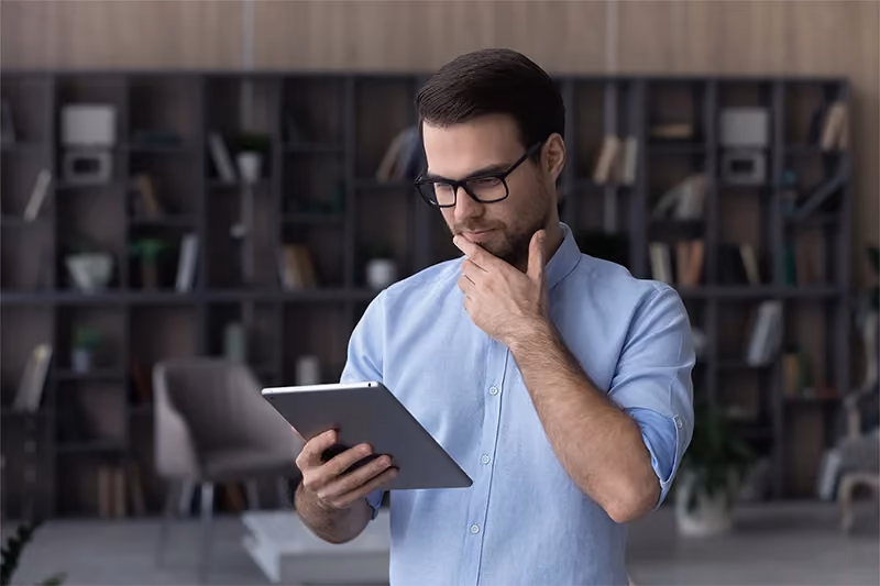 Homem lendo no tablet e refletindo sobre o impacto das redes sociais na cadeia de suprimentos.