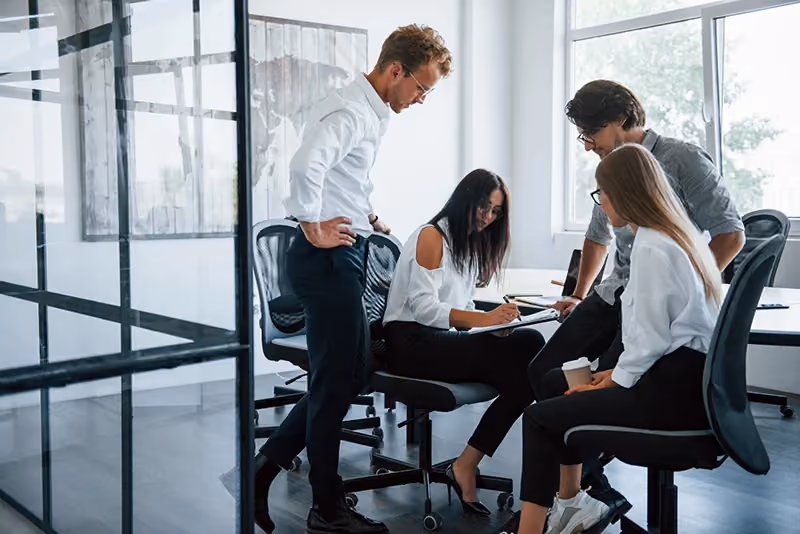 Grupo de pessoas no escritório em volta de uma mesa discutindo o que é srm.