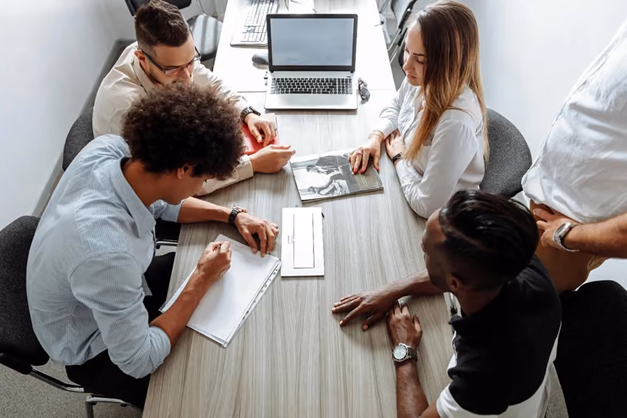 Quatro pessoas em uma sala de reunião discutindo sobre gestão de fornecedores.