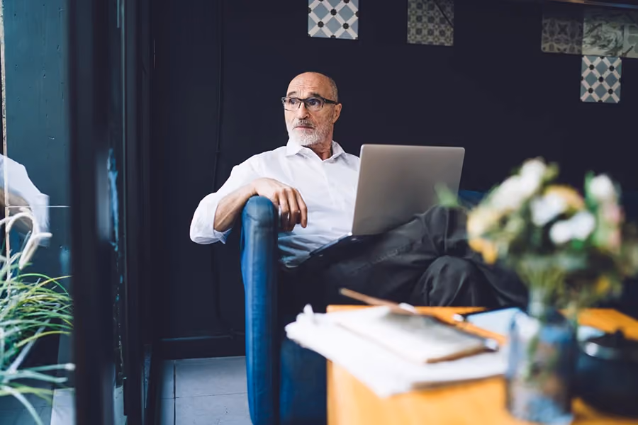 Homem sentado com laptop na mão e refletindo sobre desafios que os CEOs devem enfrentar em 2024.