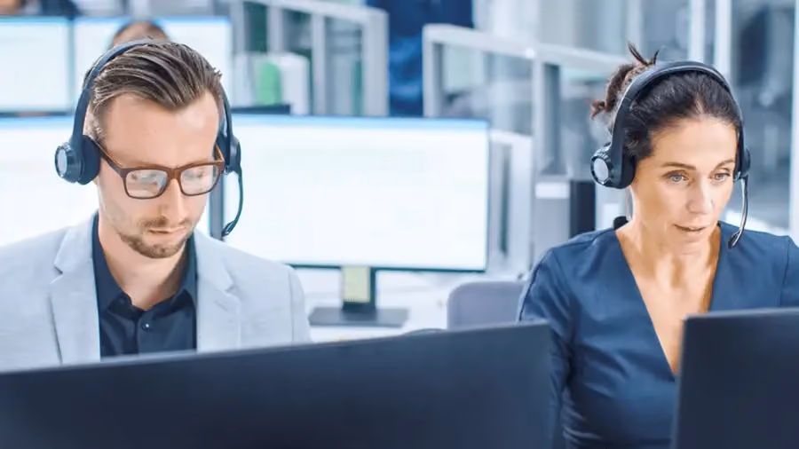 Dois profissionais com headsets em um escritório, simbolizando suporte ao cliente ou prospecção.