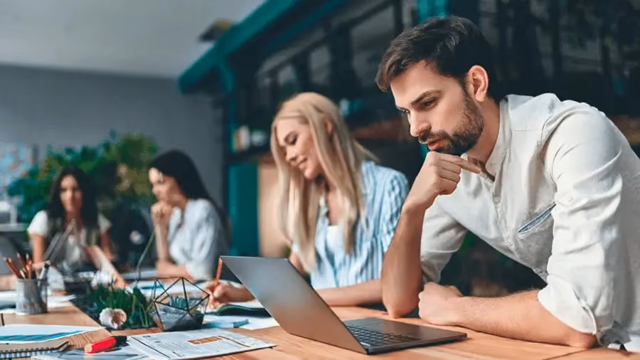 Grupo de quatro pessoas sentadas e trabalhando em um escritório.
