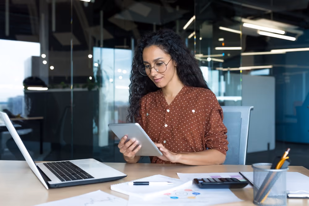 Mulher usando tablet para implementar ajustes estratégicos e garantir a regularidade fiscal da empresa