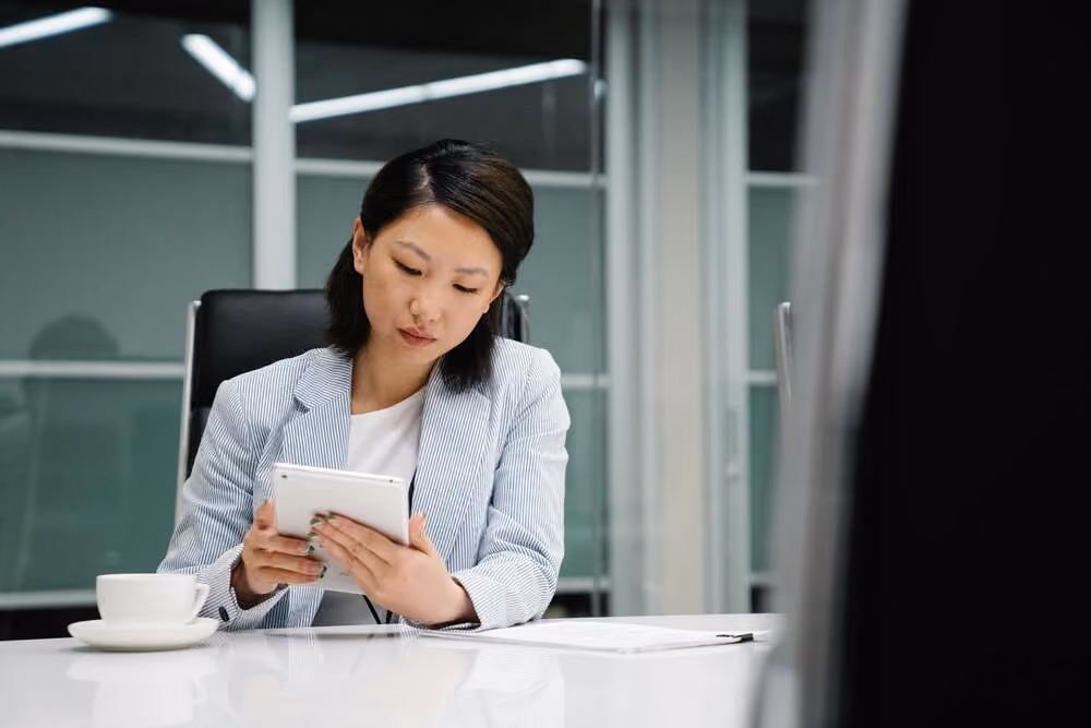 Empresária no escritório, consultando informações em um tablet para realizar o registro do Número DUNS