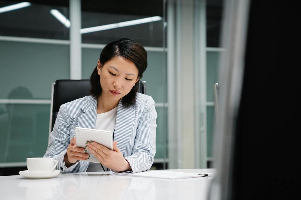 Empresária no escritório, consultando informações em um tablet para realizar o registro do Número DUNS