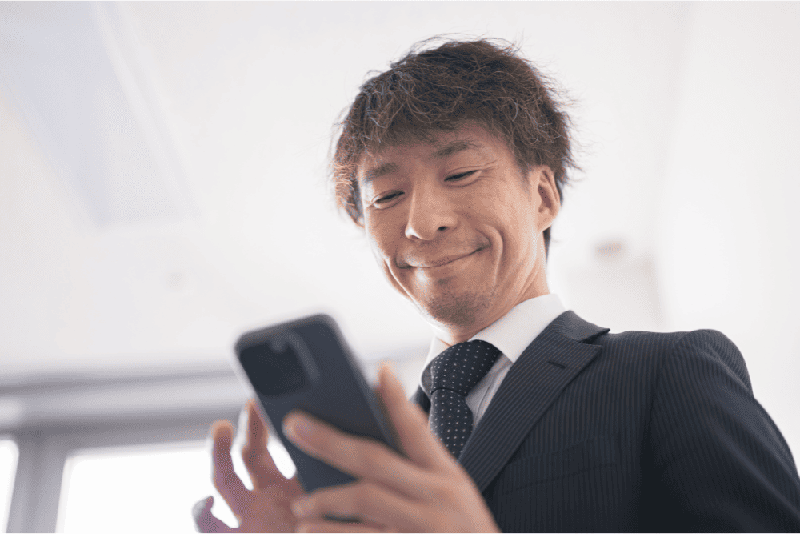 Um homem mexendo no celular sorrindo feliz com seu fornecedor
