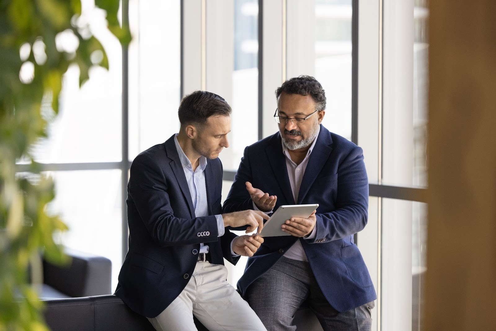 homens conversando e olhando um tablet