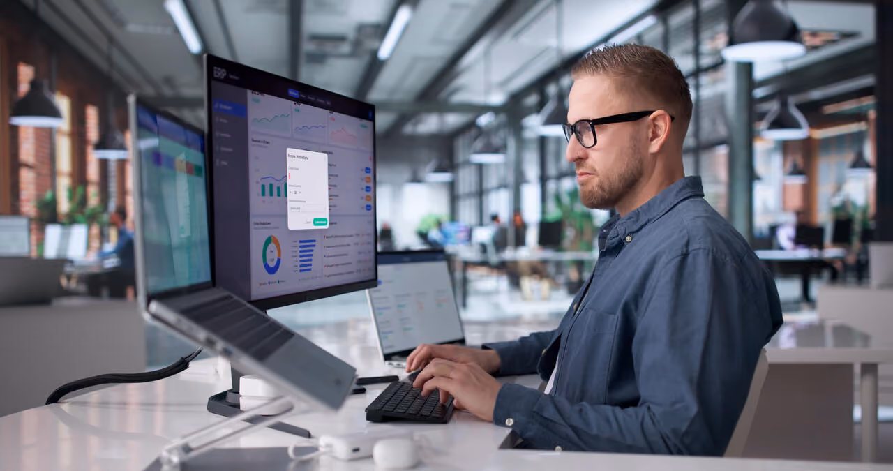 Profissional em escritório analisa dashboards em monitores para acompanhar automação de processos e indicadores de desempenho