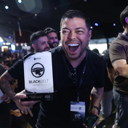 Participante sorrindo com a placa Black Belt nas mãos