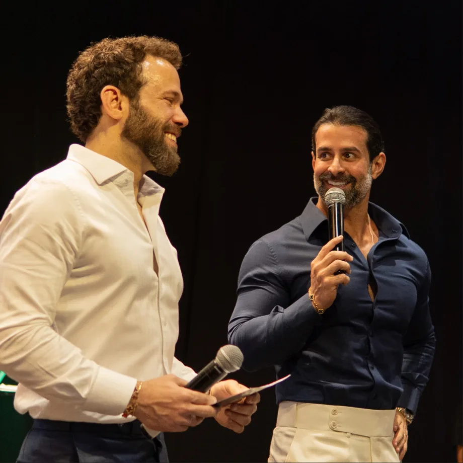 Dois participantes conversando ao microfone no palco de um evento