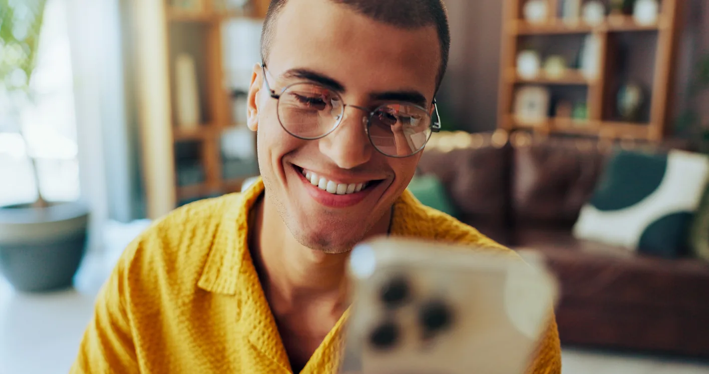 Pessoa de óculos sorrindo enquanto olha para o celular