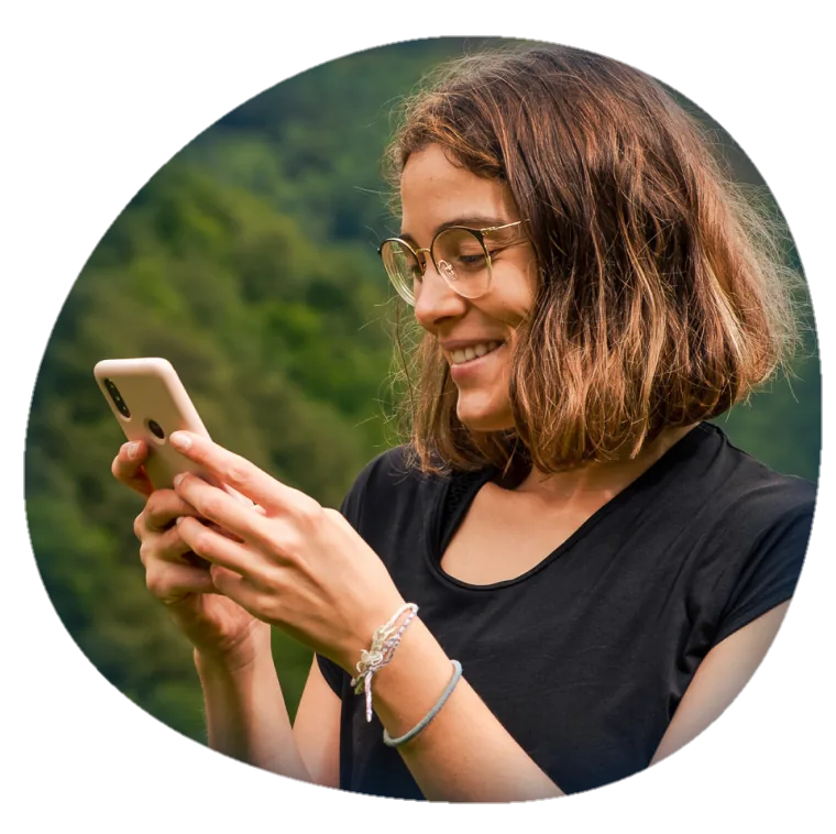 Mulher sorrindo enquanto olha para o celular ao ar livre
