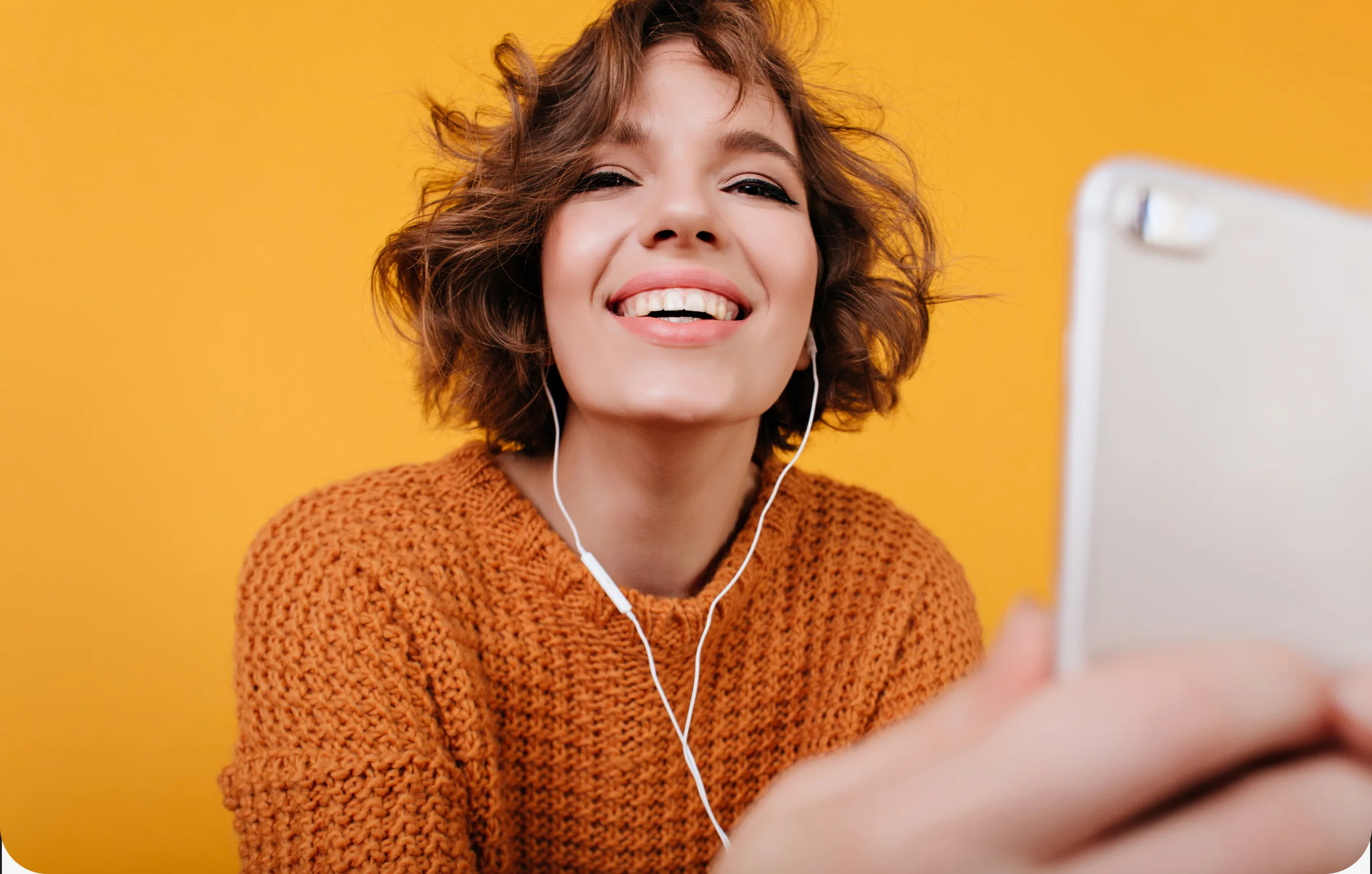 Mulher sorrindo de fones de ouvido diante da tela do computador