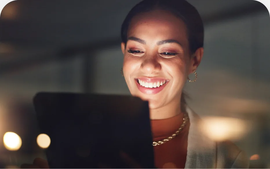 Mulher sorrindo diante da tela iluminada do notebook
