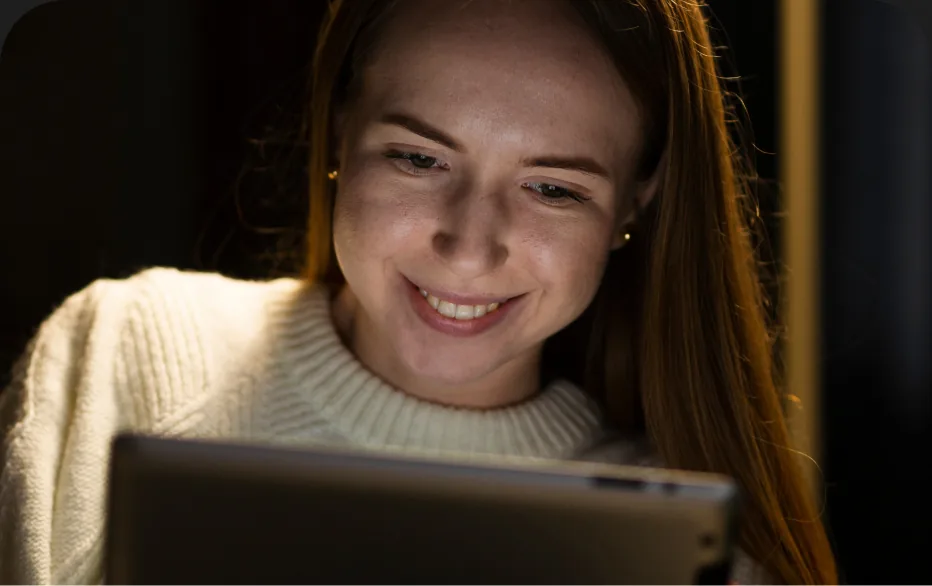 Mulher sorrindo enquanto usa o notebook em um ambiente aconchegante