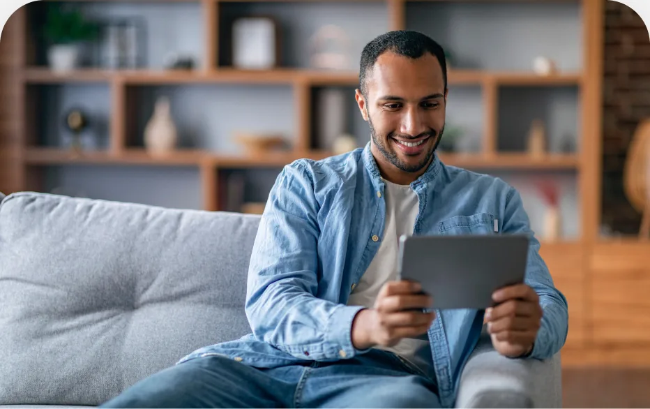 Homem sentado no sofá assistindo a um vídeo no tablet