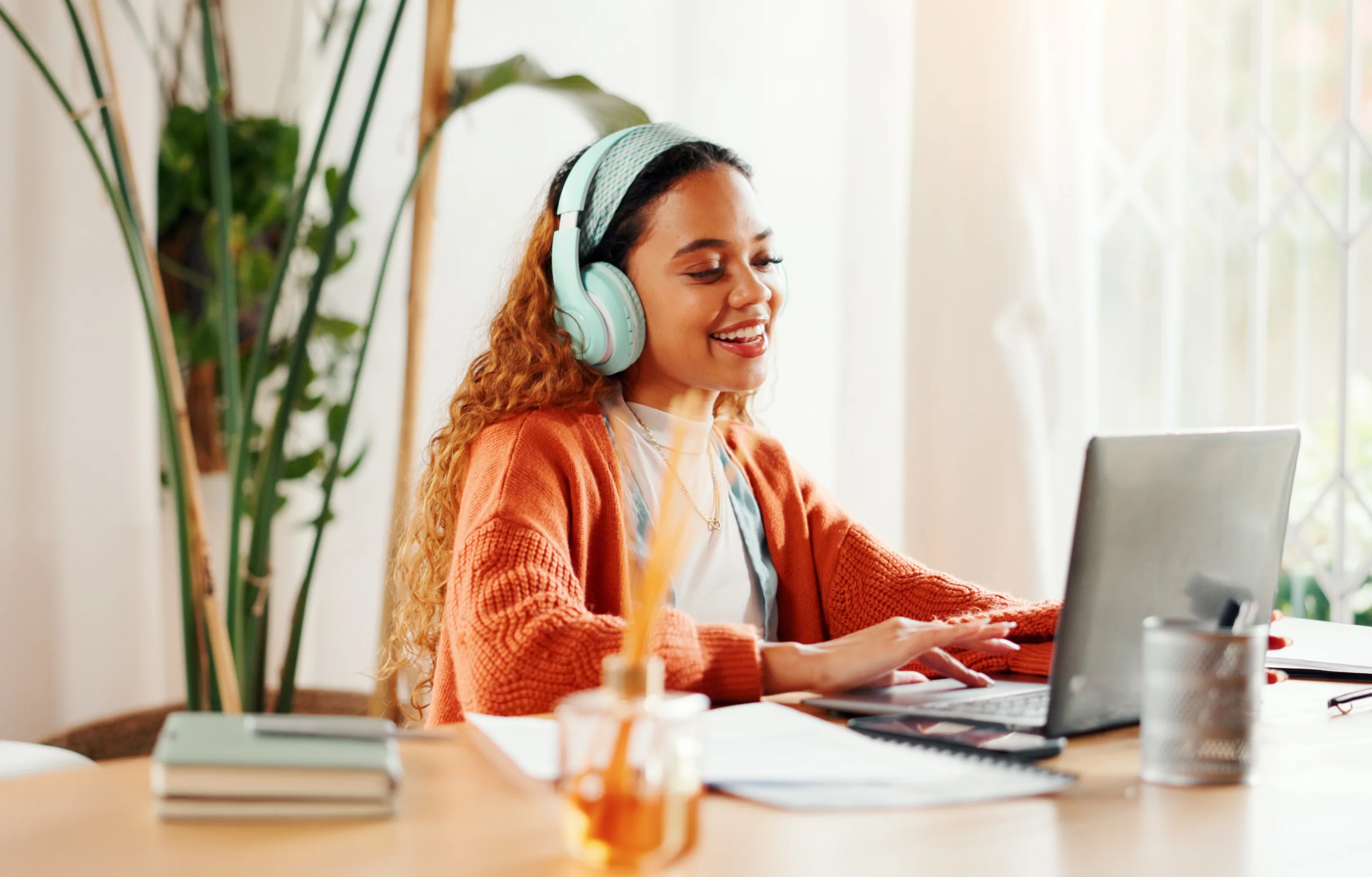 Pessoa sorrindo com fones de ouvido enquanto usa o notebook