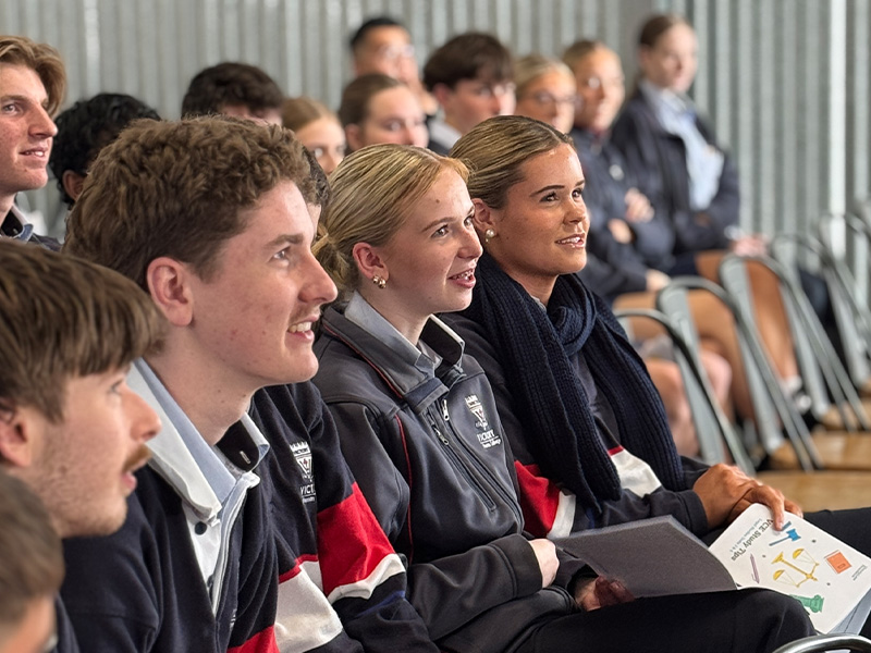Students sitting in the audience smiling and listening