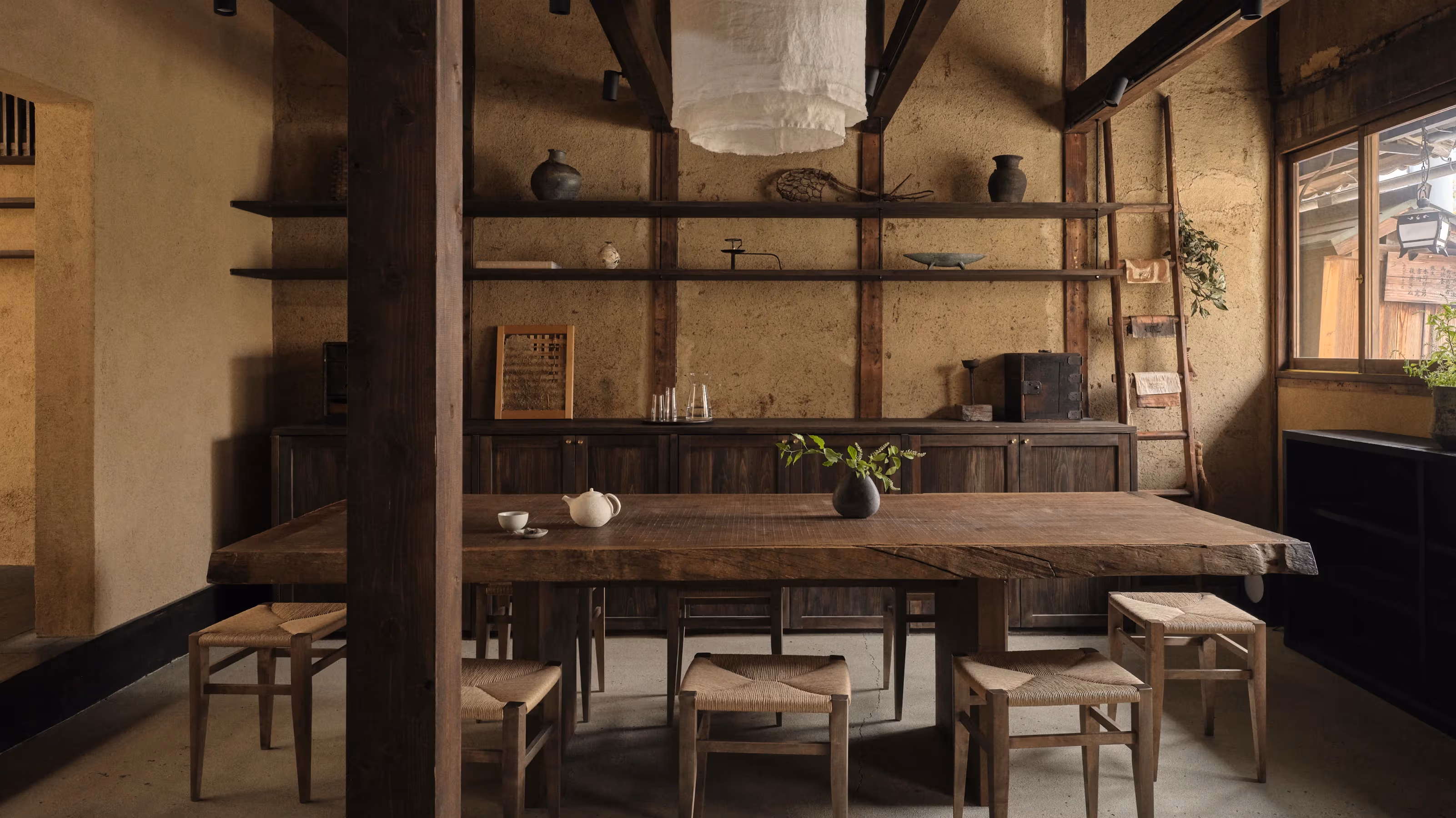 Mist-covered forest with autumn-colored trees and a narrow waterfall flowing down the hillside.