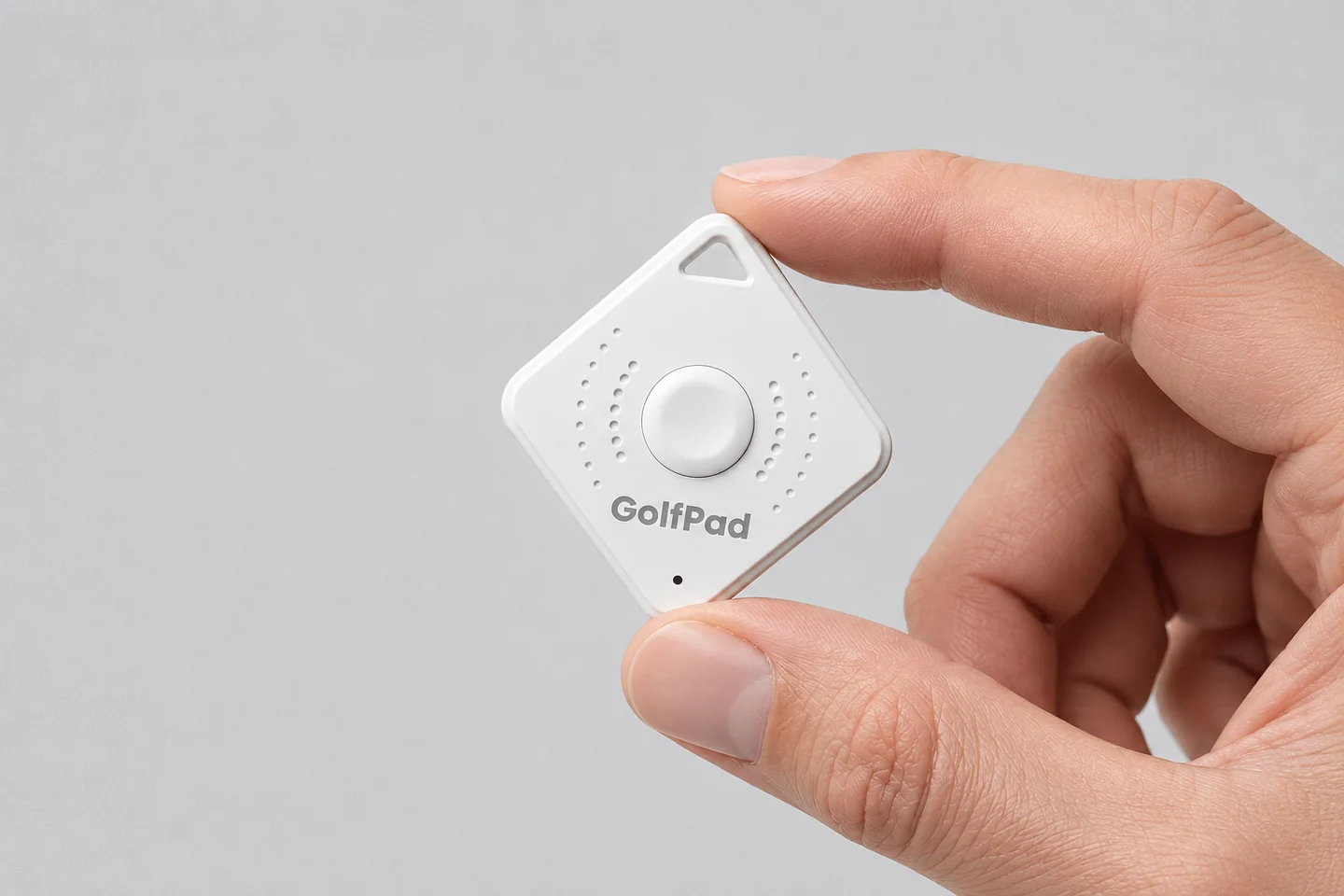 A hand holding a white Golf Pad Click Bluetooth button between thumb and finger