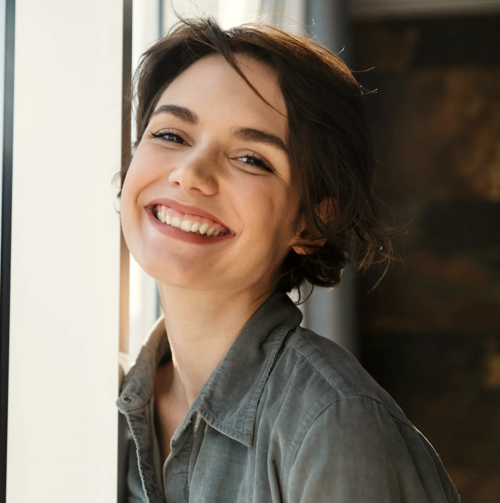 a woman smiling and leaning against a wall