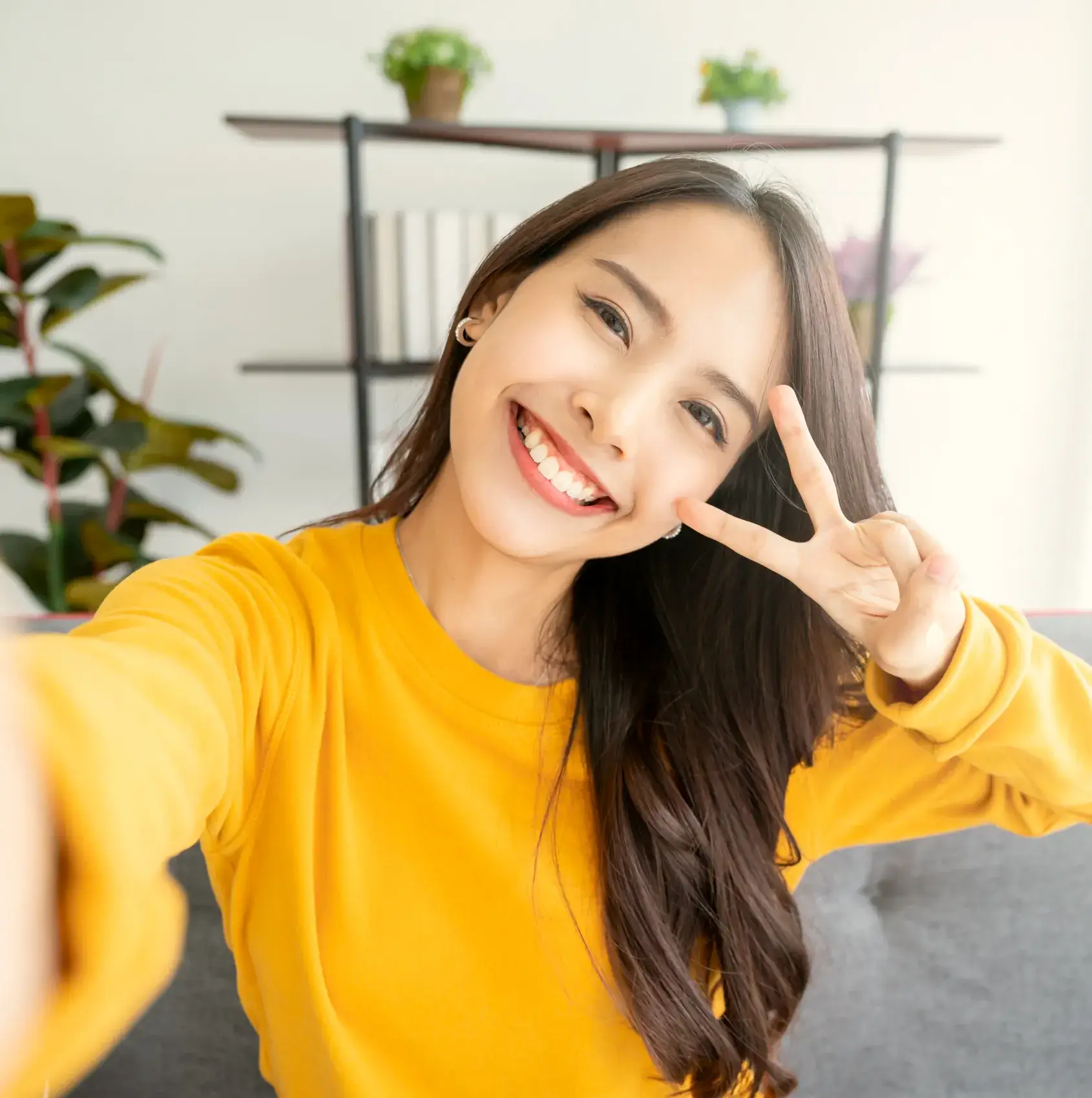 a woman in a yellow shirt making a peace sign