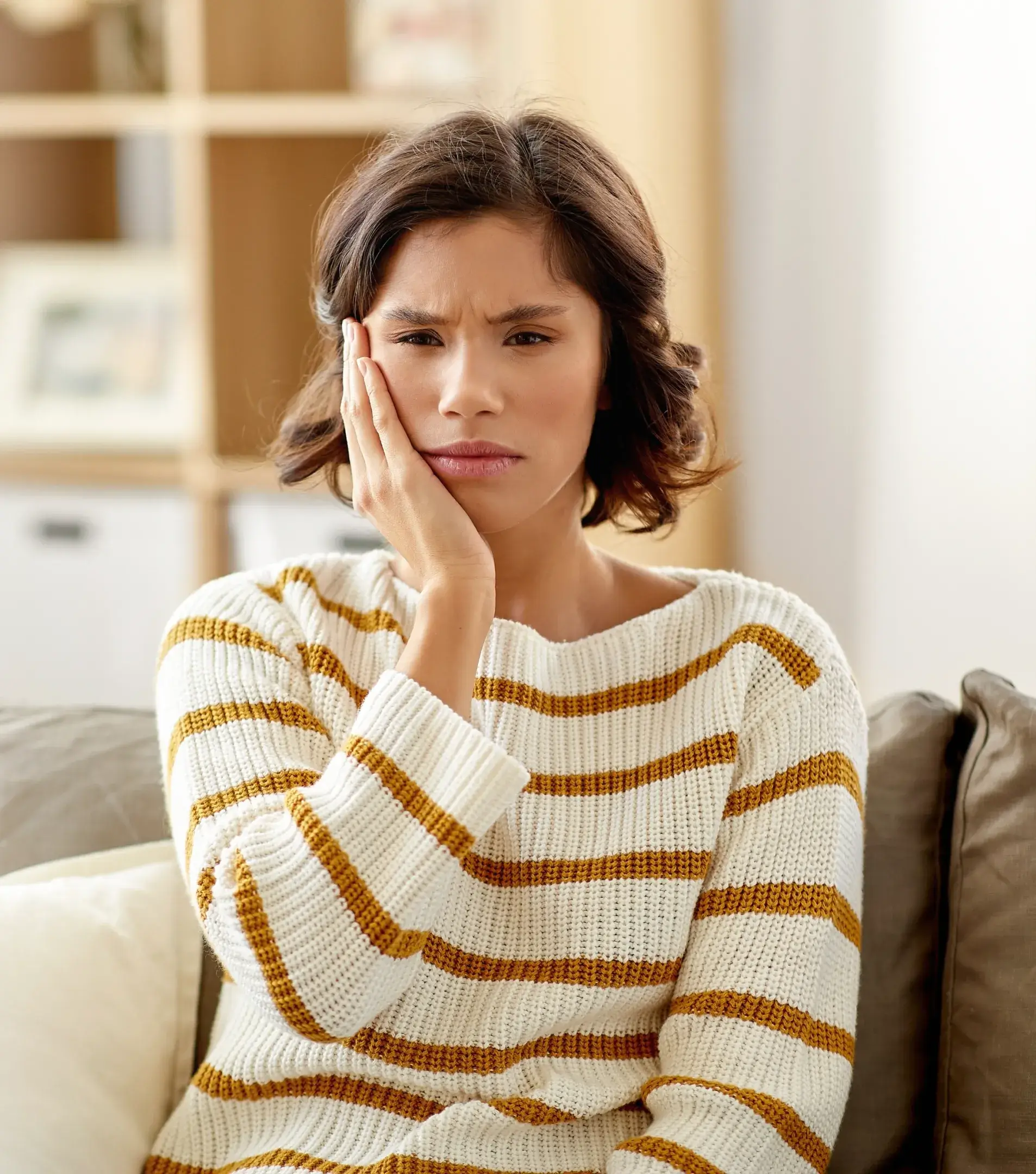a woman sitting on a couch holding her hand to her face