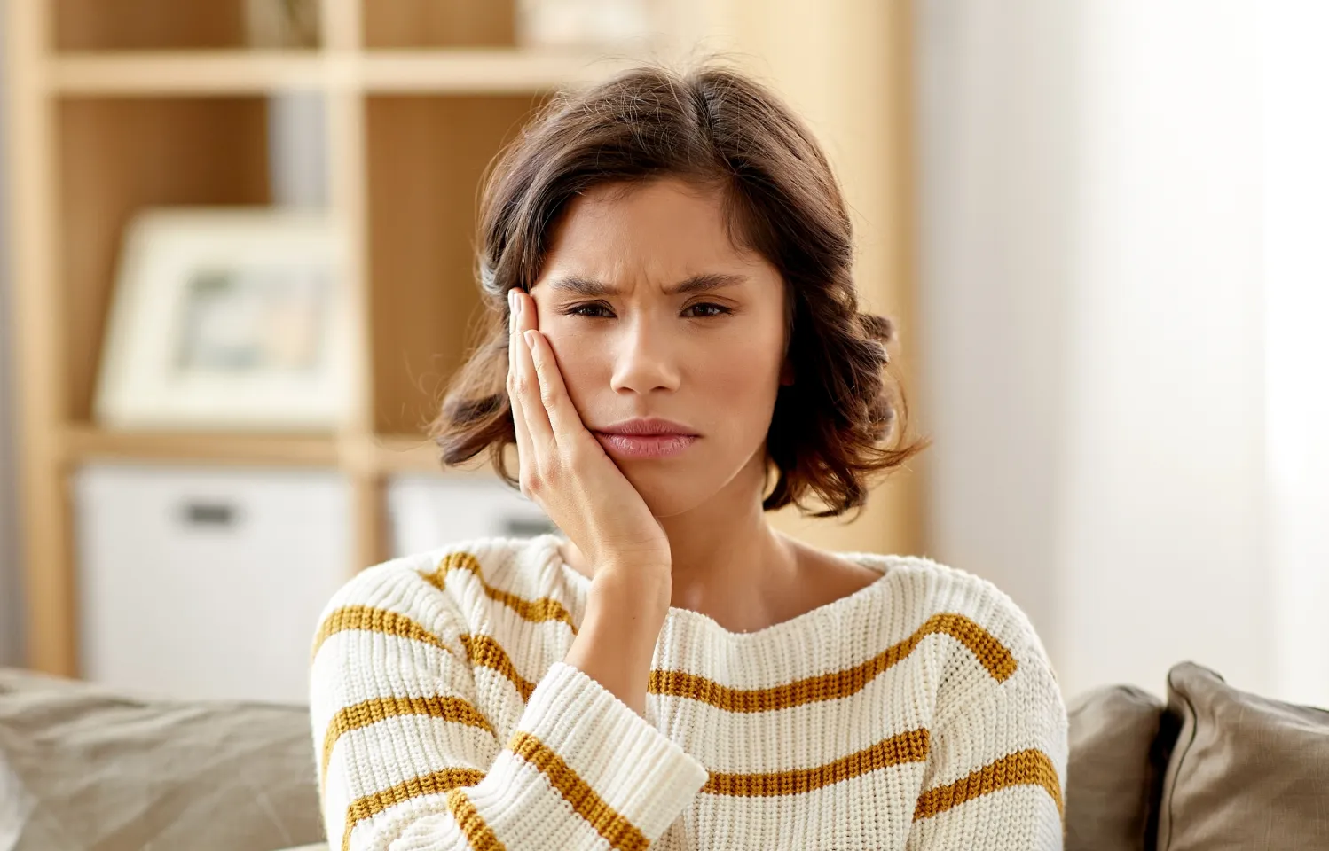 a woman sitting on a couch holding her hand to her face