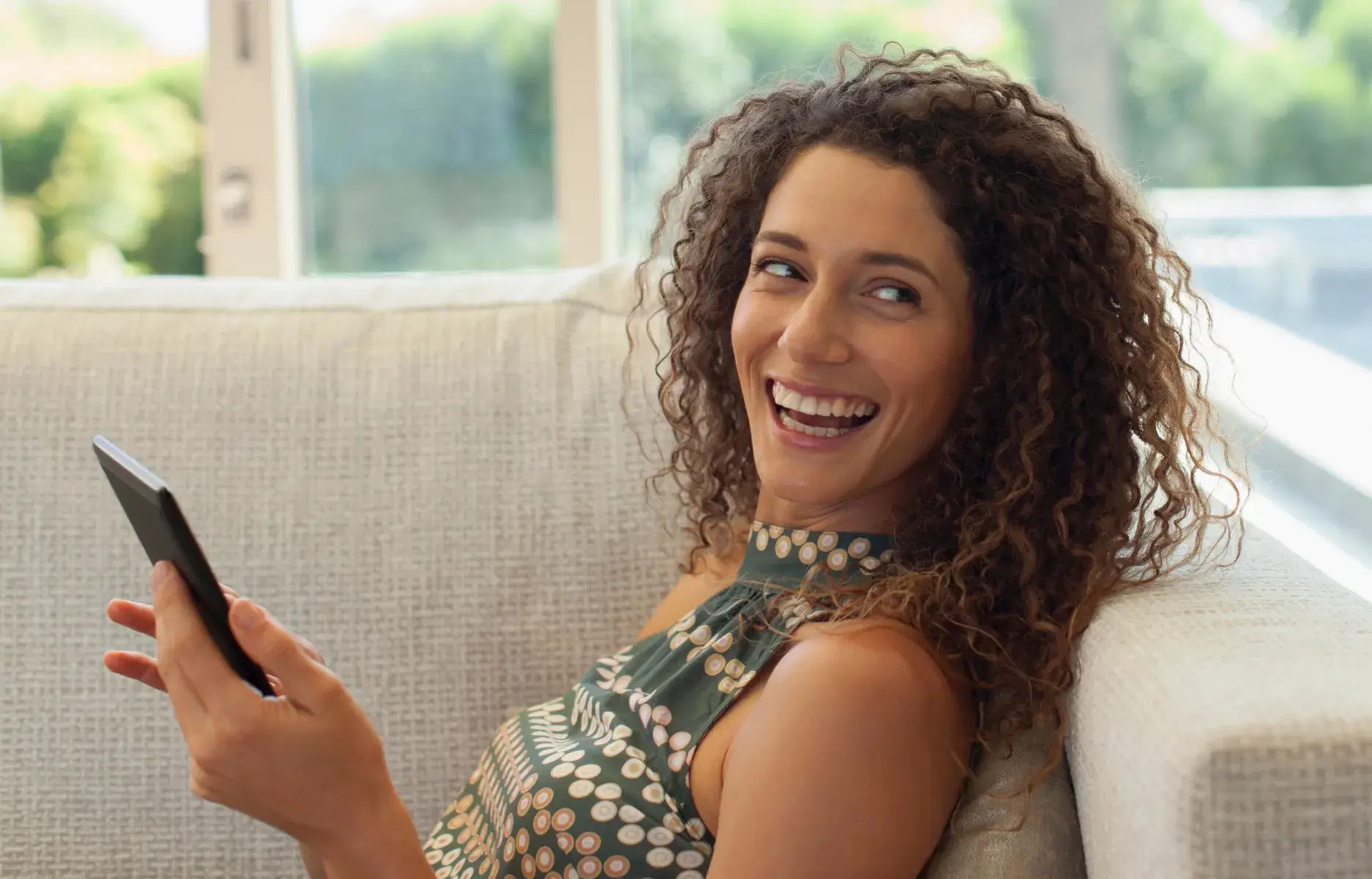 a woman sitting on a couch holding a cell phone