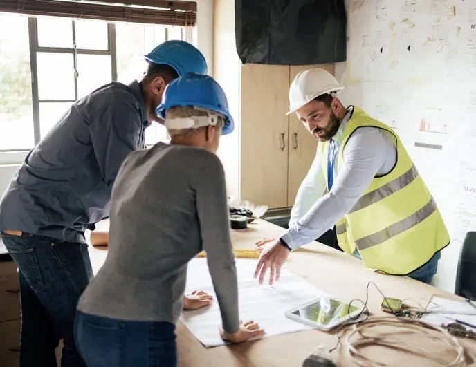 Construction workers looking a a floor plan and discussing their project