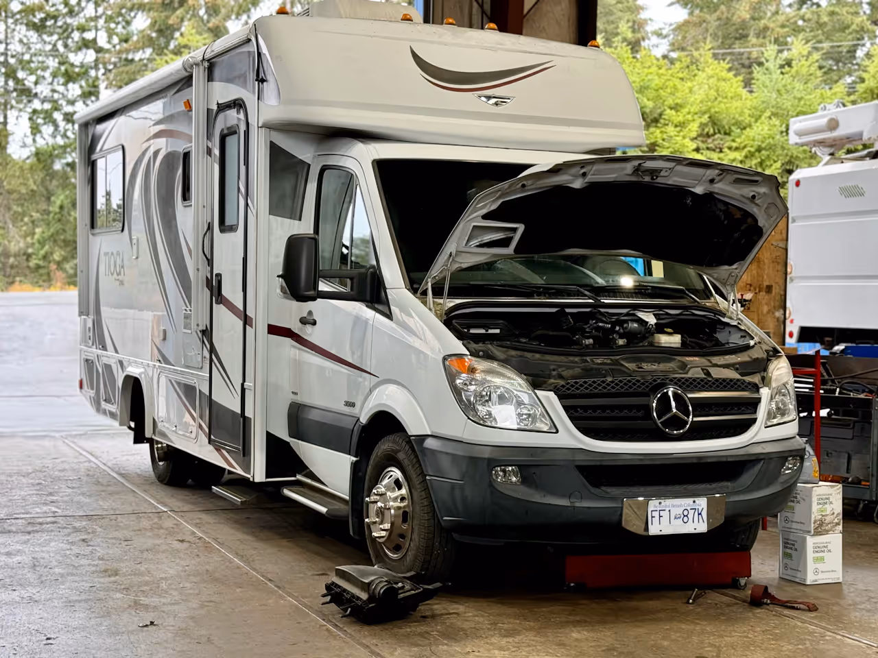 RV in a shop bay with its hood up