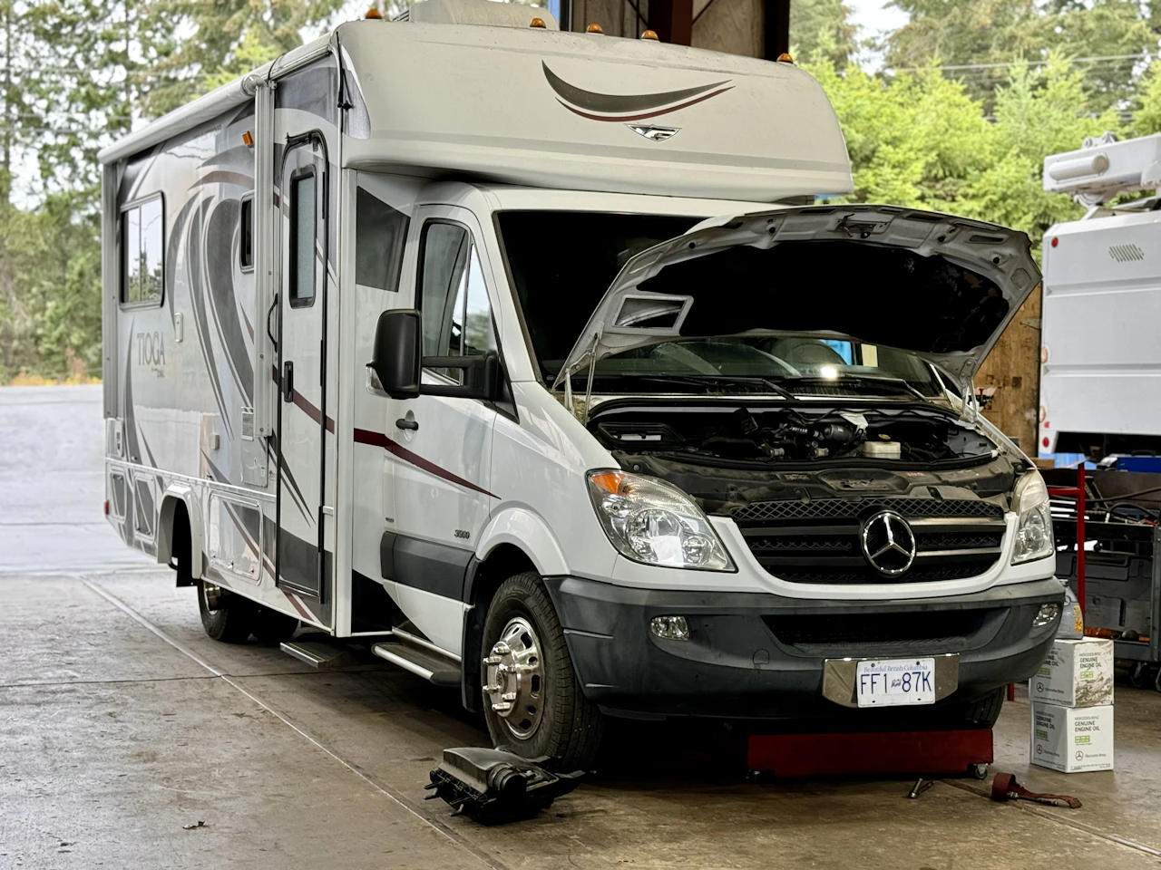 RV in a shop bay with its hood up
