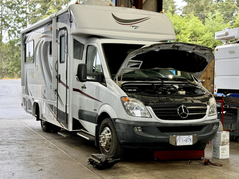 RV in a shop bay with its hood up